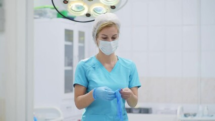 The female surgeon puts on medical protective gloves. Doctor is preparing for surgery in operation room. Medical insurance. Medicine and healthcare.