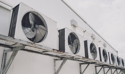 A row of split air conditioner condensers on a wall of a building