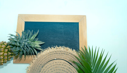 Flay lay of tropical in Summer season  and pineapple with empty bord on tropical leaves as blue  background