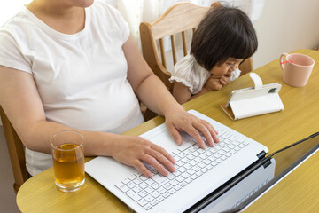 在宅勤務の母親(30代、日本人)と、スマホを見る赤ちゃん（1歳11ヶ月、日本人、女の子）