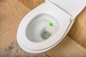 White ceramic toilet bowl in the toilet against the background of brown tiles. View from above. No...