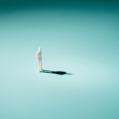Man plastic figurine standing alone on a gradient blue background. Mental health futuristic concept.
