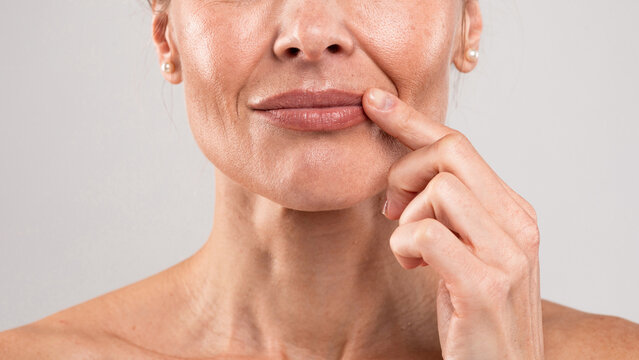 Middle Aged Woman With Wrinkles On Face Touching Lips With Finger, Closeup