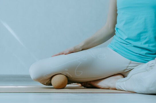Self myofascia release of adductors with corkmassage ball on cork mat with white background. Concept: self care practices at home, knee pain relief, SMFR