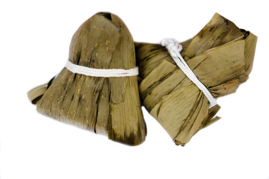 Sticky Rice dumpling or Bajang in Thai language, made from  steamed rice ,grains, pork, salty eggs ,nut, wrapped in dry leaves in pyramid shape isolated on white background. Concept : Chinese dessert.