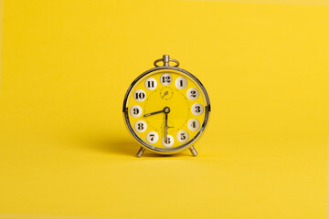 Round yellow alarm clock on a bright yellow background with space for copy