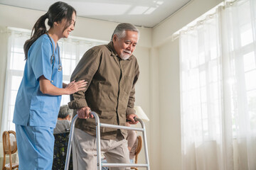 young asian female nurse care giver helping asian senior old man with mobility walker in living...
