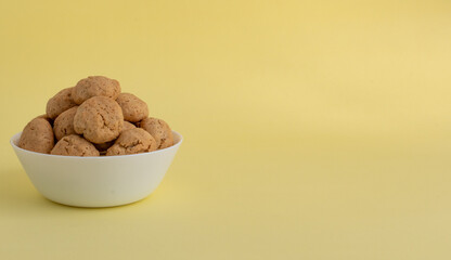 Oatmeal cookies on a white plate on a yellow background with space for text on the right. Healthy food concept. High-quality photo
