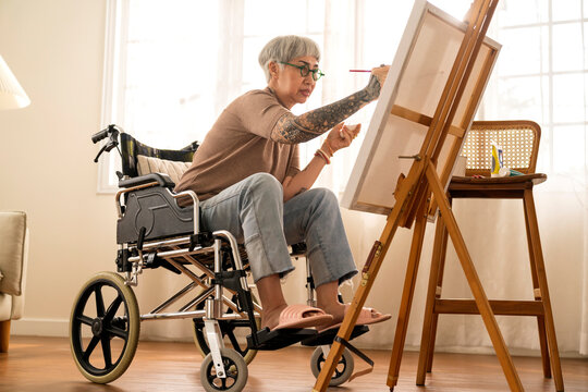 Old Senior Asian Female Tattoo Using Art Therapy While His Legs Is Injured At Home,asian Elder Woman Spend Recovering Of Her Leg Is Getting Better With Painting Canvas Art In Living Room At Home