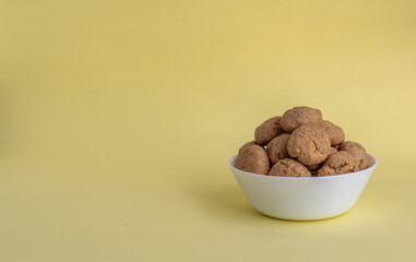 Oatmeal cookies on a white plate on a yellow background with space for text on the left. Healthy food concept. High-quality photo