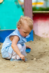 Girl playing with toys in the sandbox in the yard