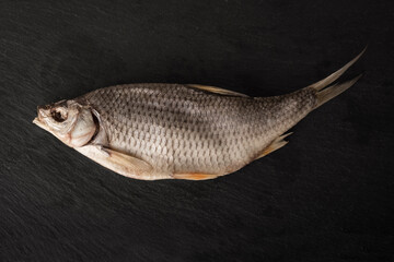 Dried fish on a black background. Sun-dried, salted roach close-up