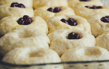 Raw buns with cherries in a glass form, side view
