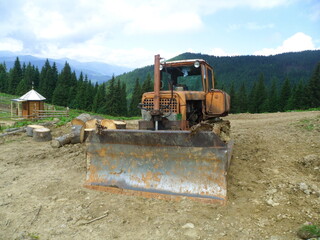 A bulldozer makes a road in the mountains