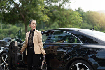 Asian mature business success woman disembarking the luxury car