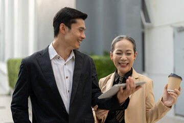 Portrait of young and senior business people working together with digital tablet outdoor.