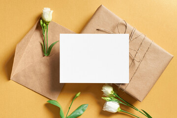 Greeting card mockup with gift box and white flowers on gold