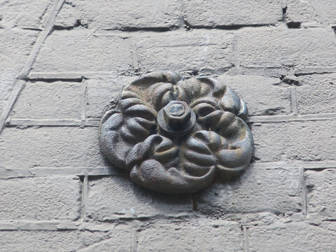cast iron wall anchor or builder on a gray painted brick wall