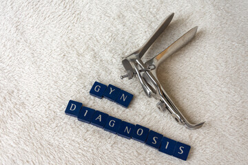 speculum with the words gyn diagnosis on a white blanket