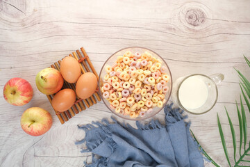 top view of colorful cereal corn flakes, apple , egg and milk on table 