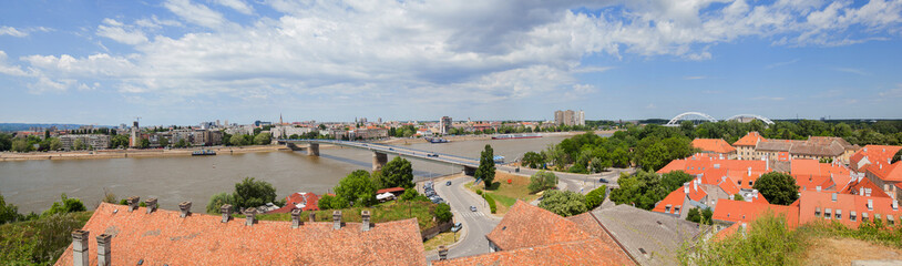 Obraz premium Cityscape of Novi Sad, bridge over Danube river. Panoramic view. Downtown at riverside. Cloudy spring day at noon. Serbia. Europe.