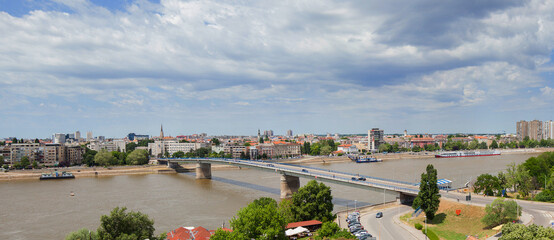 Cityscape of Novi Sad, bridge over Danube river. Panoramic view. Downtown at riverside. Cloudy spring day at noon. Serbia. Europe.