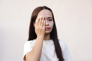 Asian woman covering her eyes with her hand