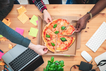 Friends sharing pizza at startup home office or coworking space