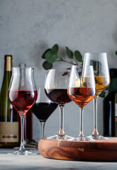 Wine glasses and bottles assortment. Red, white, rose wines on gray table background. Wine bar,...