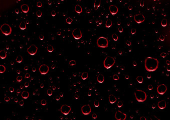 Water drops on glass transparent in red color.