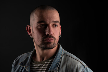 Fototapeta premium handsome man with calm bristled view in jeans jacket isolated in studio on black background