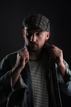 mature casual man in denime jacket holding collar by hands. Man in berette on black background studio