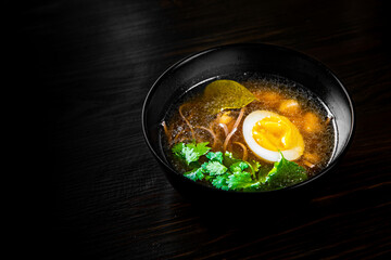 Japanese ramen soup with tofu and egg on black wooden table background