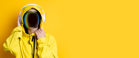 Young woman in cyberpunk glasses with headphones in a yellow jacket on a yellow background. Banner