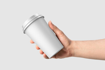 Paper coffee cup with plastic cap in a hand mockup template, isolated on light grey background....