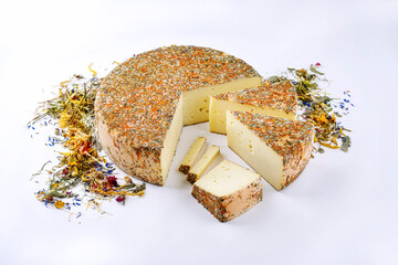 Traditional aged hay flower mountain cheese loaf of the Alps offered as loaf and sliced on white...
