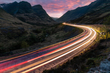 Fototapeta Car light trails on winding road through the highlands near Glencoe in Scotland at dusk obraz