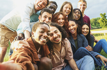 Cheerful multiethnic friends having fun taking selfies outdoors during a picnic - Group of diverse...