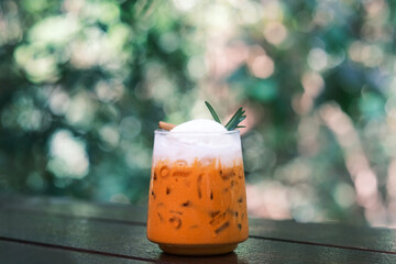 Thai Milk Tea, Milk ice tea, Cheddar is a traditional Thai drink that has long been popular, fresh and sweet dessert on a wooden saucer, vintage wooden table in cafe.