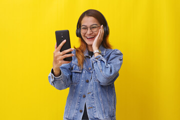Excited young asian woman standing while using a cellular phone.Lifestyle concept isolated on yellow