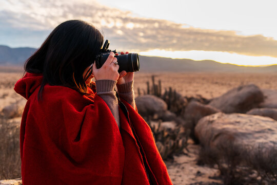 portrait woman photographer taking pictures in the desert at sunset