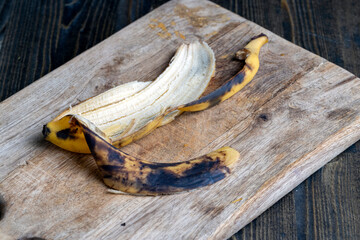 Fototapeta premium old blackening banana on a cutting board, perishable banana fruit food