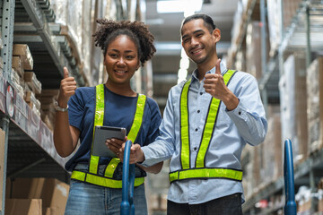 African American female employee hold tablet in a warehouse and an Asian male employee thump up together in wholesale shop