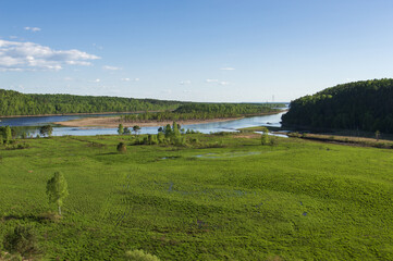 landscape of a field with a river and a forest