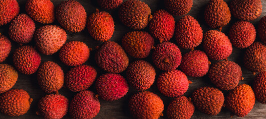 Red ripe litchi on the wooden table. Shot from above. Background and textures.