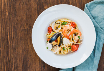 Pasta spaghetti with seafood sauce copy space top view with mussels, clams, shrimps on wooden...