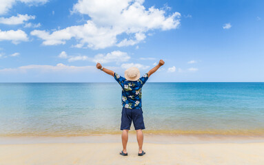 Young Asian man raise his hands up by the sea, vacation time,