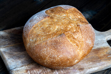 a whole loaf of bread on a cutting wooden board