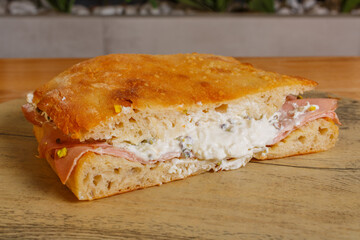 Pizza romana cotta al forno ripiena di mortadella, stracciata di bufala e granella di pistacchio servita per pranzo in una rosticceria