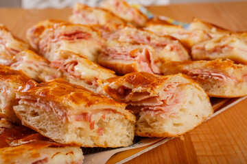 Piccole pizzette di pasta sfoglia ripiene di mozzarella e prosciutto cotto pronte per un buffet 